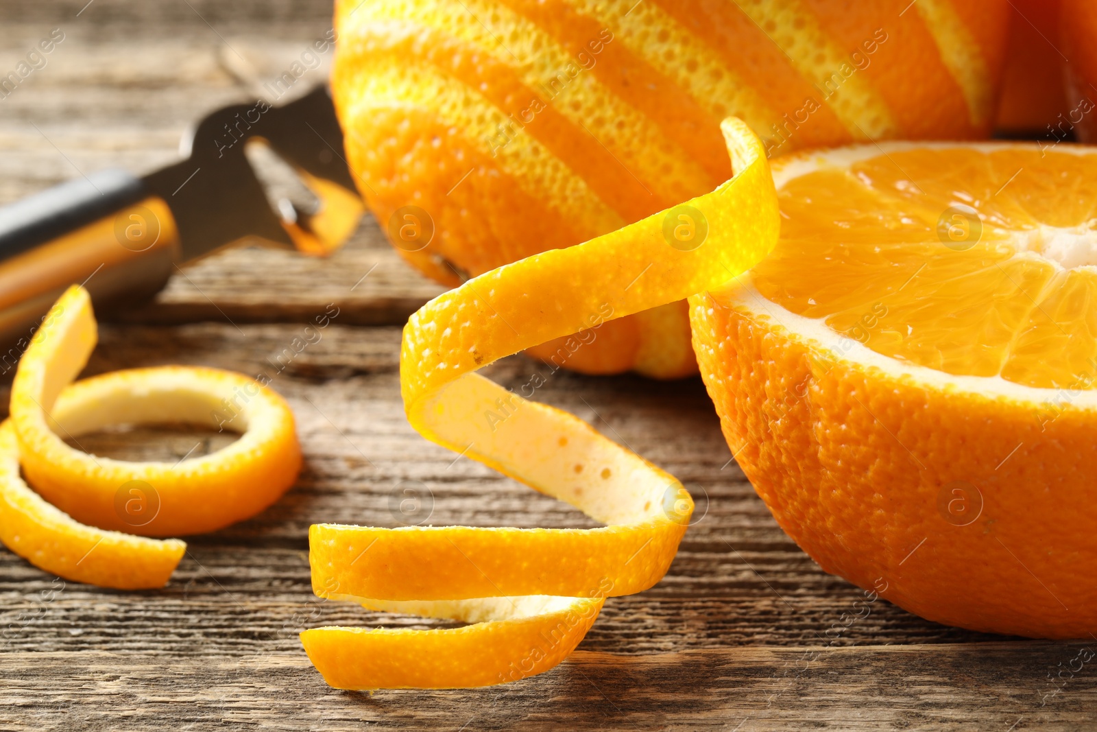 Photo of Fresh orange peels and fruits on wooden table, closeup