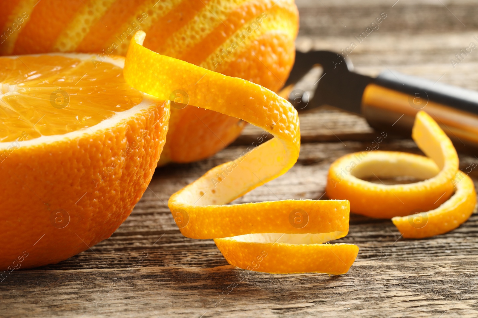 Photo of Fresh orange peels and fruits on wooden table, closeup