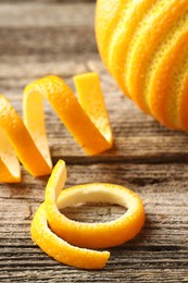 Photo of Fresh orange peels and fruit on wooden table, closeup