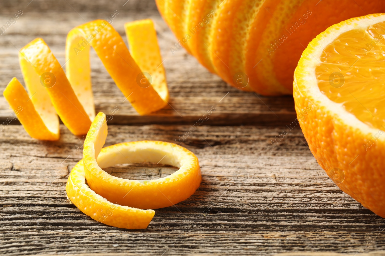 Photo of Fresh orange peels and fruits on wooden table, closeup