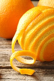 Photo of Fresh orange peel and fruits on wooden table, closeup