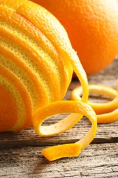 Photo of Fresh orange peel and fruits on wooden table, closeup