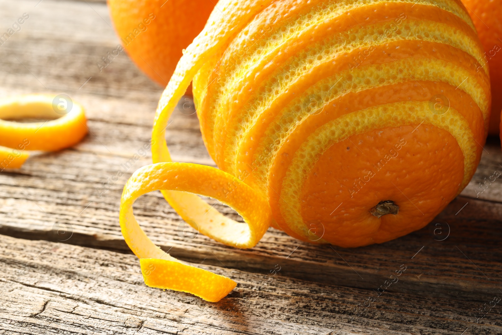 Photo of Fresh orange peel and fruit on wooden table, closeup