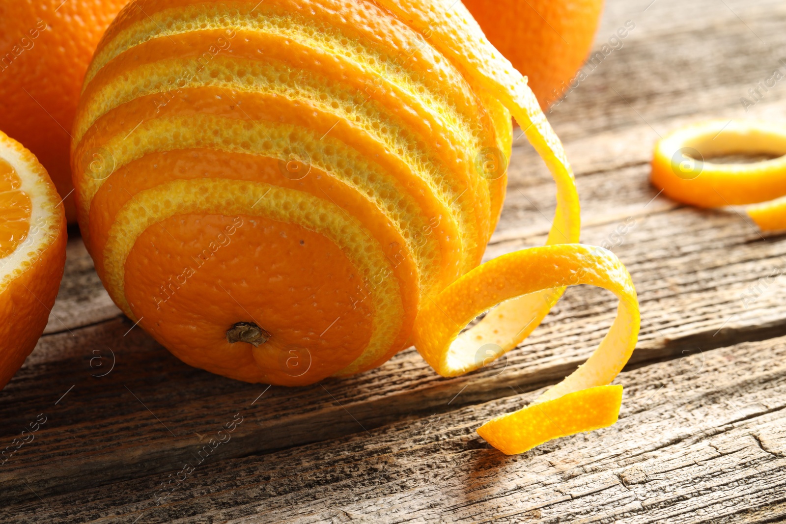 Photo of Fresh orange peel and fruit on wooden table, closeup