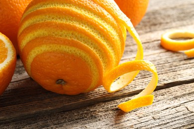 Fresh orange peel and fruit on wooden table, closeup