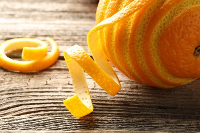 Photo of Fresh orange peels and fruit on wooden table, closeup