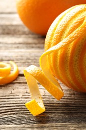 Fresh orange peels and fruit on wooden table, closeup