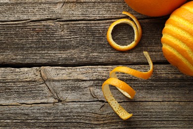 Photo of Fresh orange peels and fruits on wooden table, flat lay. Space for text