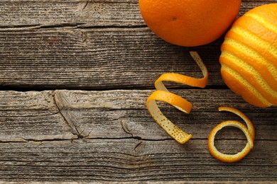 Photo of Fresh orange peels and fruits on wooden table, flat lay. Space for text