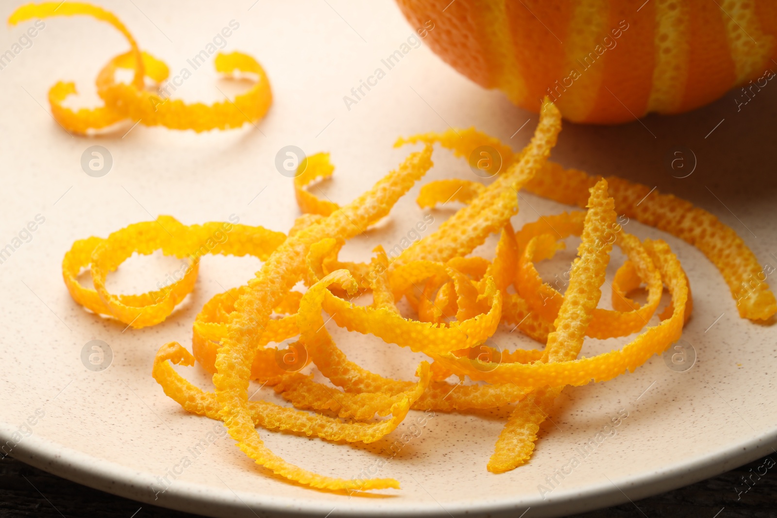 Photo of Fresh orange zest and fruit on plate, closeup