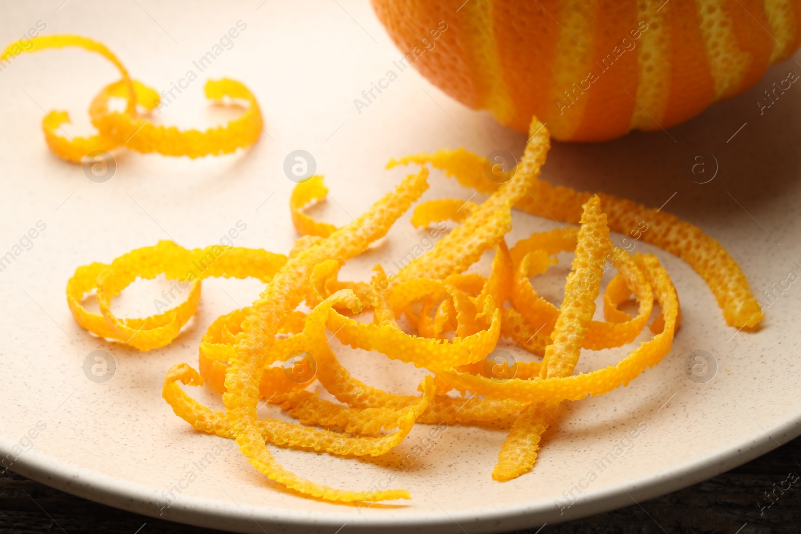 Photo of Fresh orange zest and fruit on plate, closeup