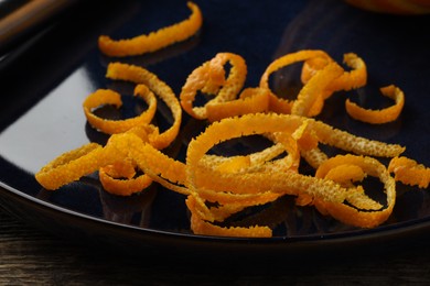 Photo of Plate with fresh orange zest on wooden table, closeup