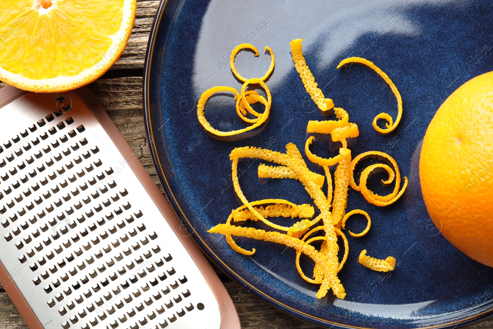 Photo of Fresh orange zest, fruits and grater on wooden table, flat lay