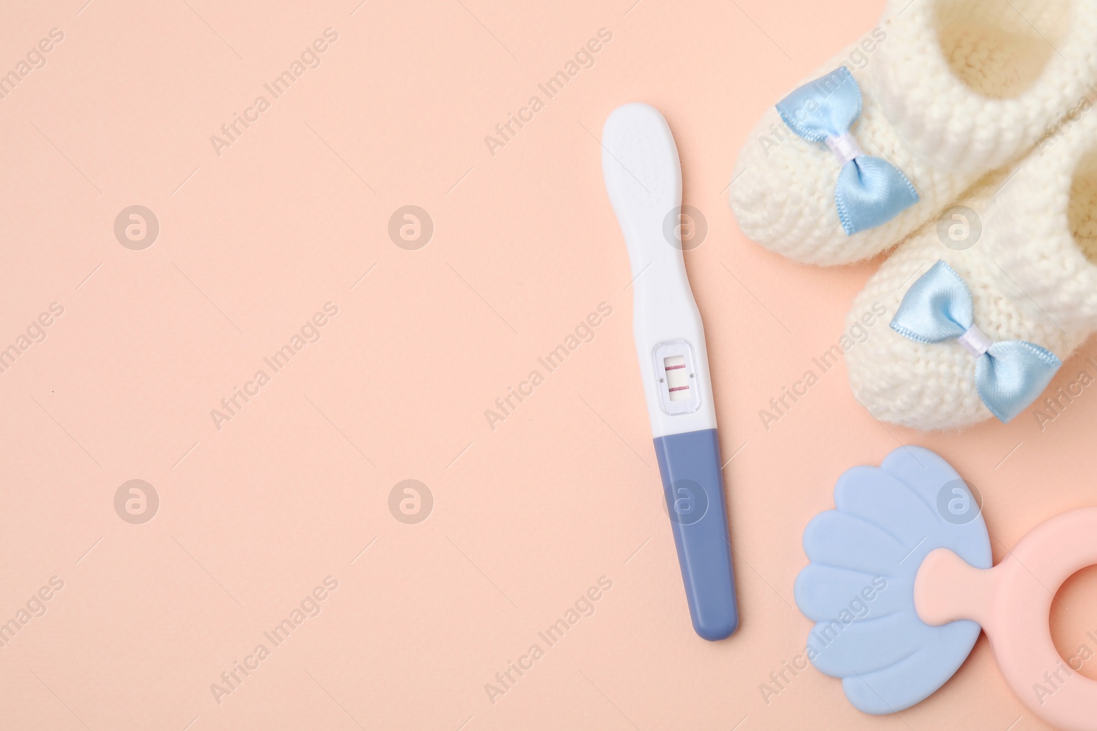 Photo of Pregnancy test, baby shoes and toy on pink background, flat lay. Space for text