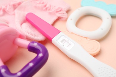 Photo of Pregnancy test, baby socks and toys on pink background, closeup