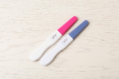 Photo of Two pregnancy tests on white wooden table, top view