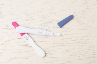 Photo of Two pregnancy tests on white wooden table, top view