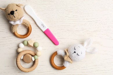 Photo of Pregnancy test and baby toys on white wooden table, flat lay. Space for text