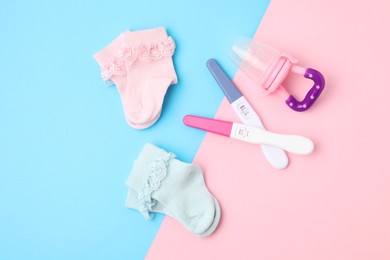 Pregnancy test, baby socks and toy on color background, flat lay