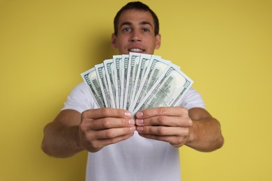 Photo of Man with dollar banknotes on yellow background, selective focus