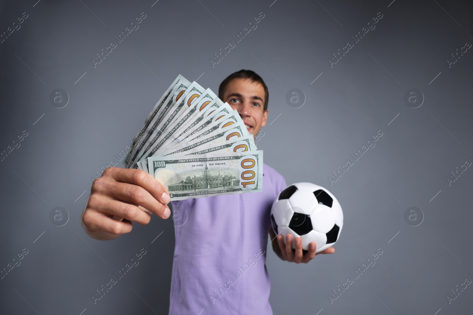 Photo of Man with money and soccer ball on grey background, selective focus