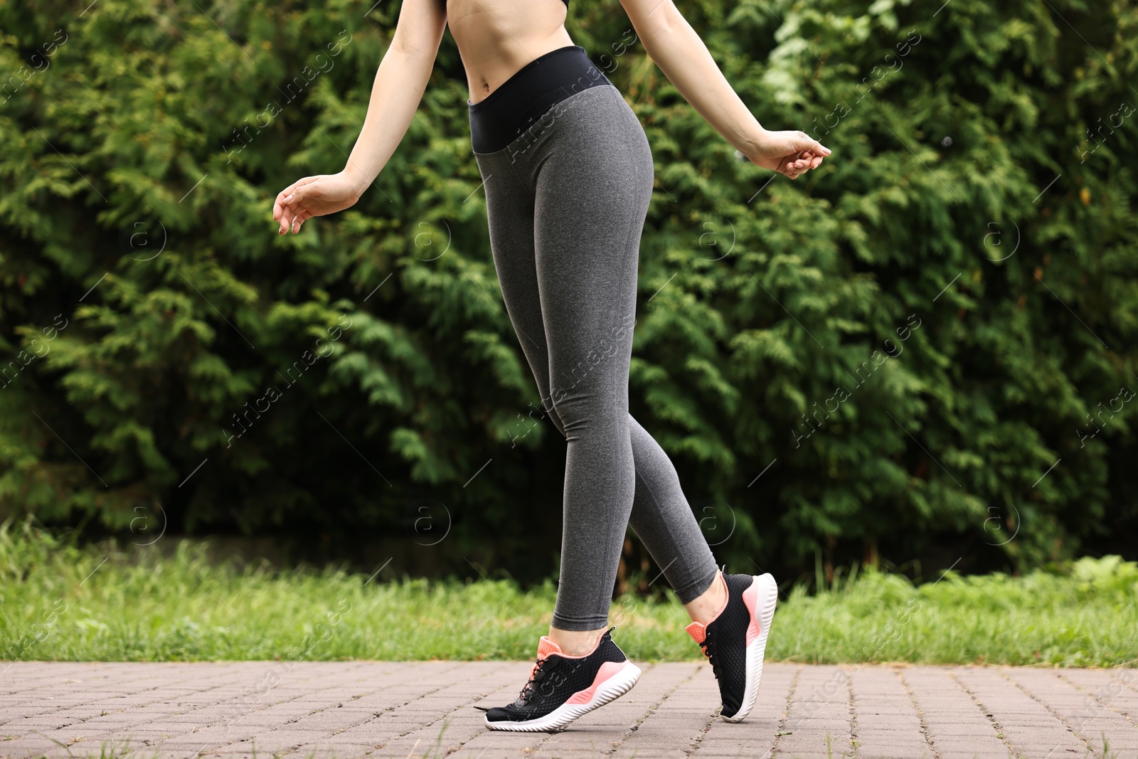 Photo of Woman wearing stylish sports leggings outdoors, closeup