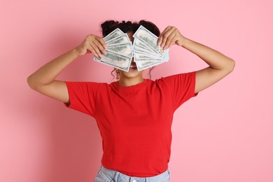 Photo of Woman covering eyes with dollar banknotes on pink background