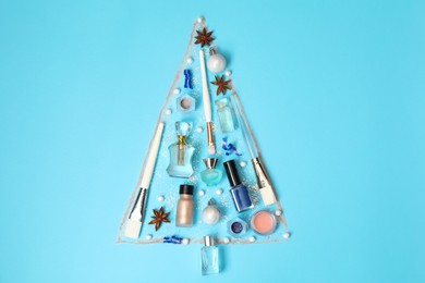 Christmas tree made of perfume bottles and makeup products on light blue background, flat lay