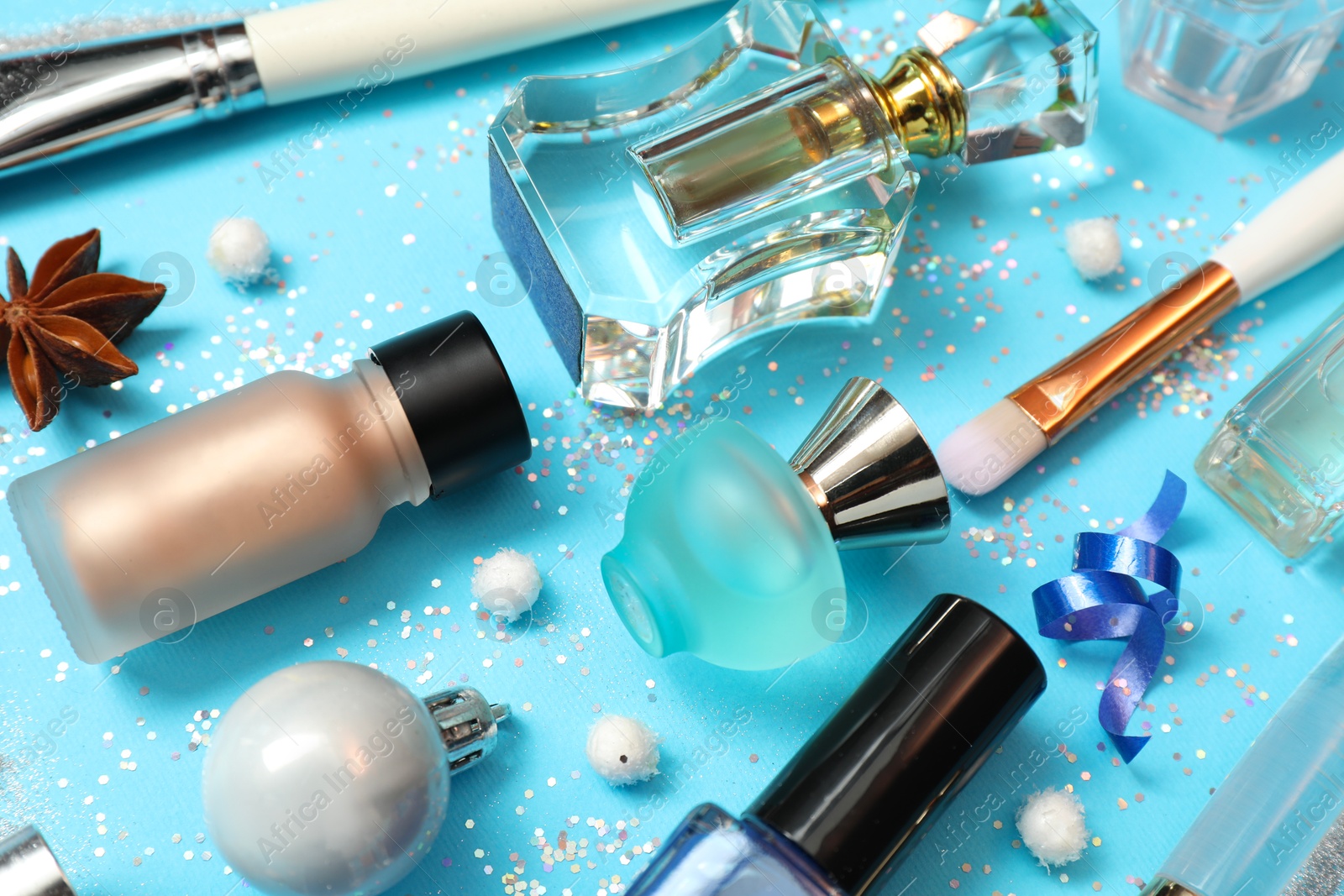 Photo of Perfume bottles and makeup products on light blue background, closeup