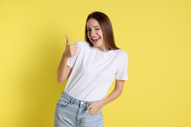 Happy winner showing thumbs up on yellow background