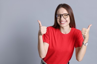 Happy winner showing thumbs up on gray background, space for text