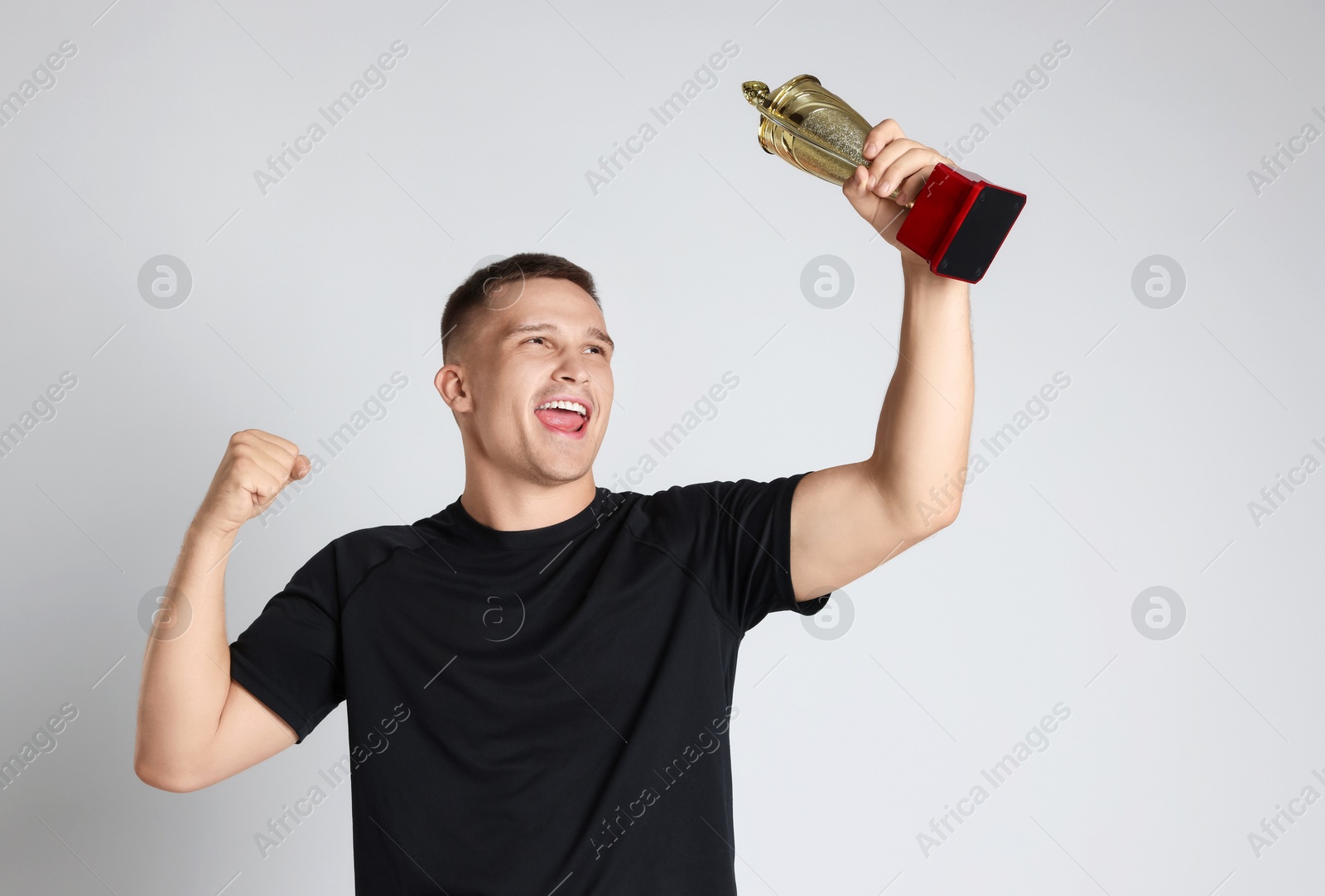 Photo of Happy winner with golden trophy cup on light grey background