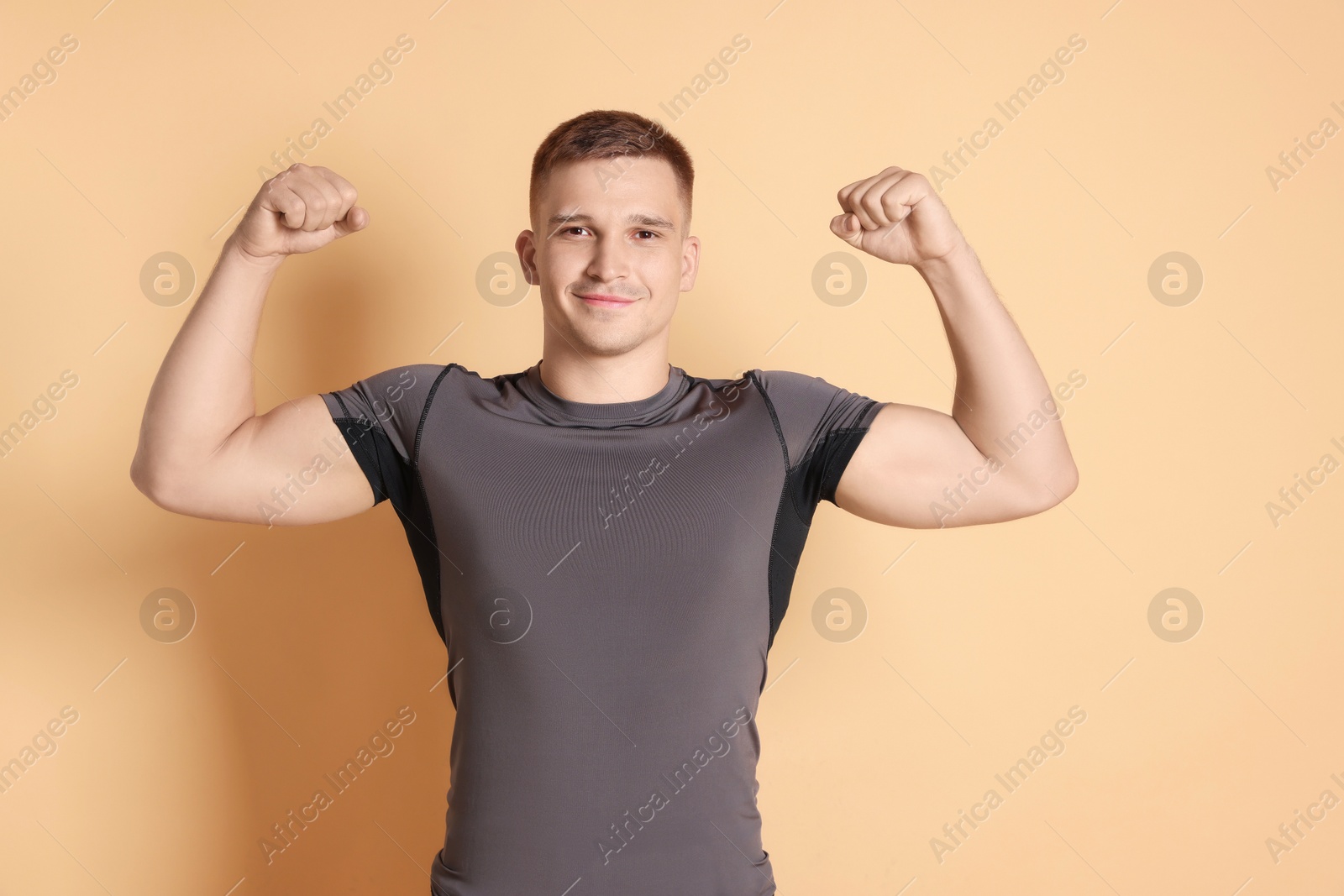 Photo of Smiling winner showing his biceps on beige background