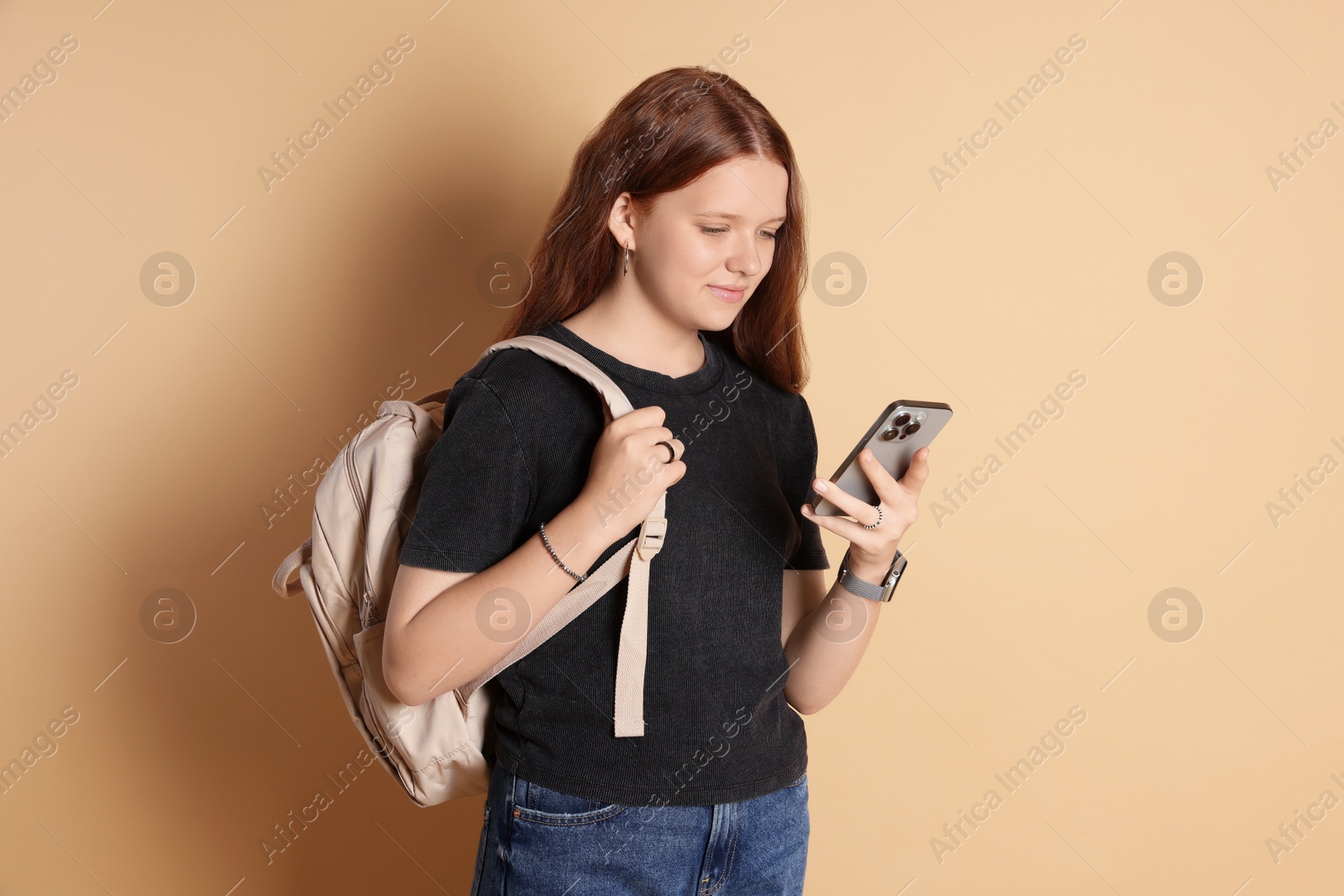 Photo of Cute teenage girl with smartphone on beige background