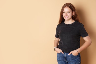 Smiling teenage girl posing on beige background. Space for text