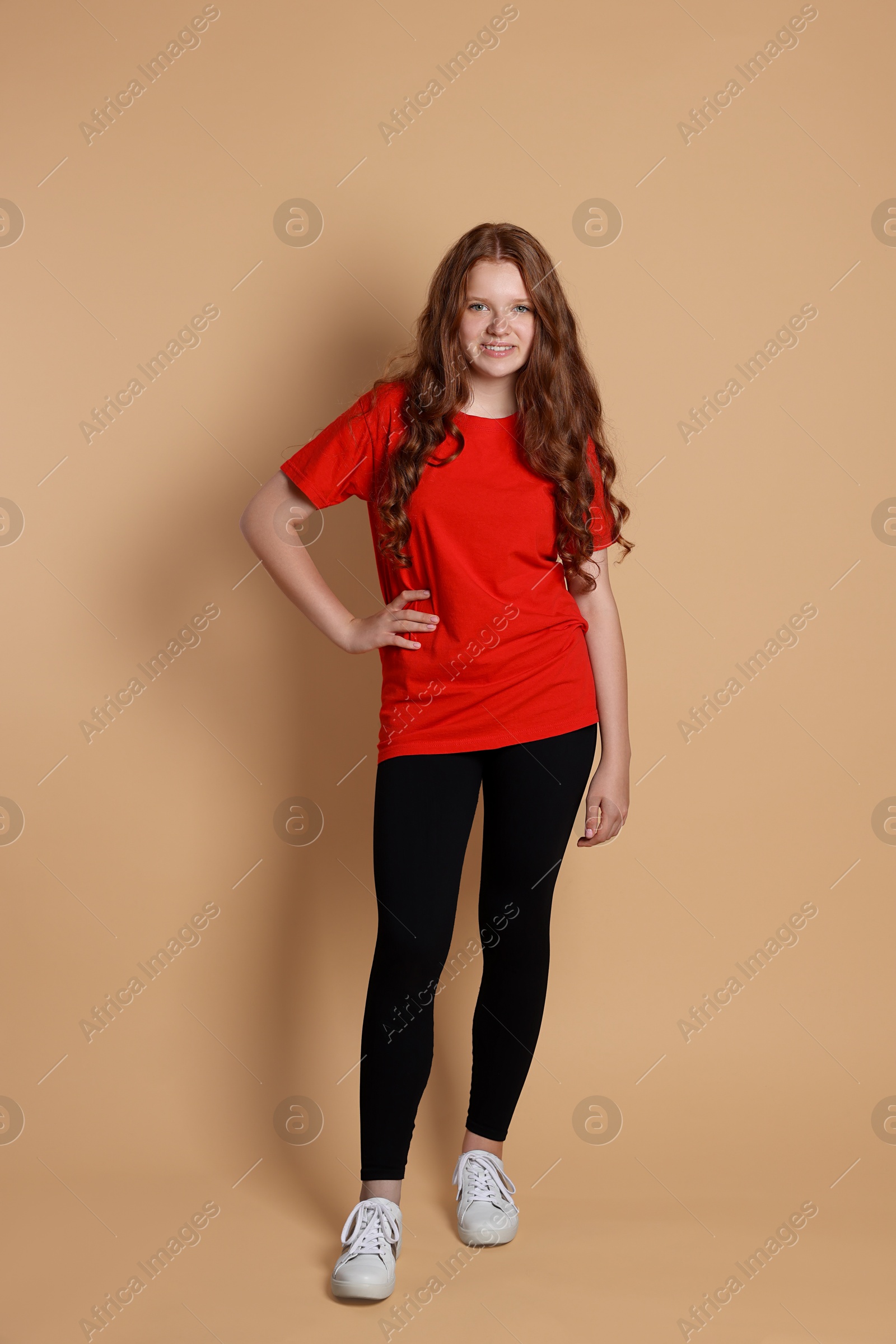 Photo of Smiling teenage girl posing on beige background