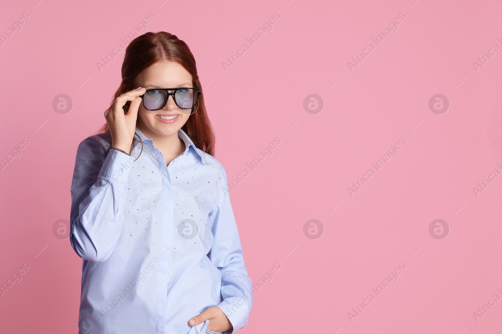 Photo of Happy teenage girl in sunglasses posing on pink background. Space for text