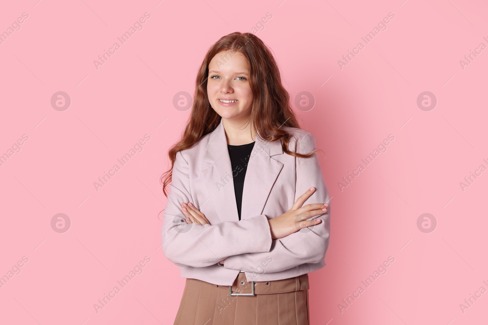 Photo of Smiling teenage girl with crossed arms on pink background