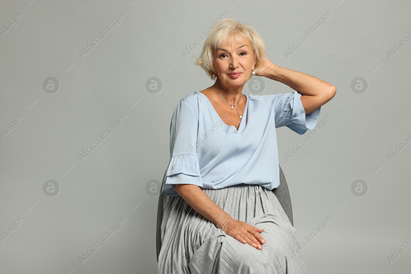 Photo of Beautiful senior woman sitting on chair against light grey background