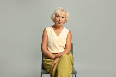 Photo of Beautiful senior woman sitting on chair against light grey background