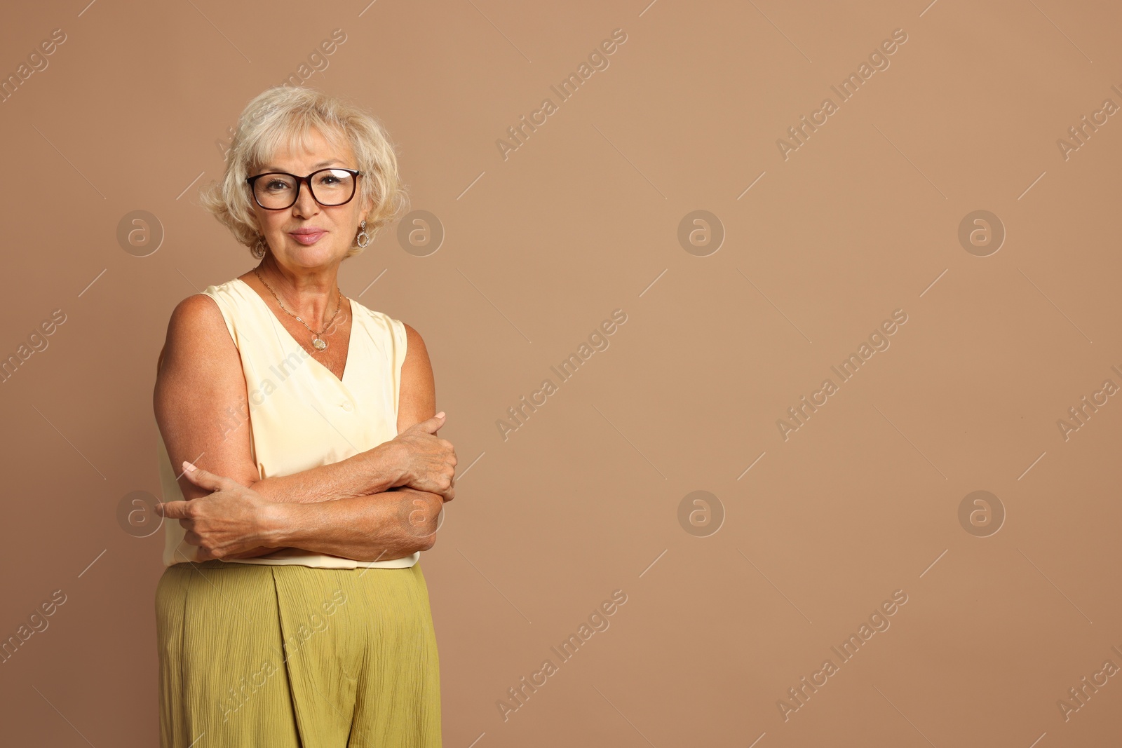 Photo of Portrait of beautiful senior woman on light brown background, space for text