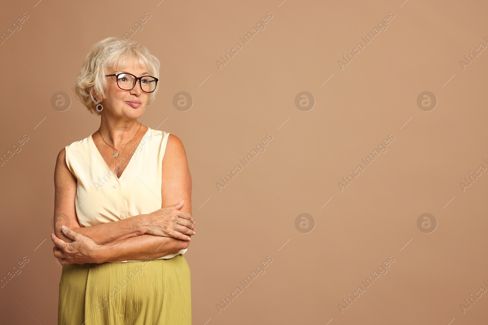 Photo of Portrait of beautiful senior woman on light brown background, space for text