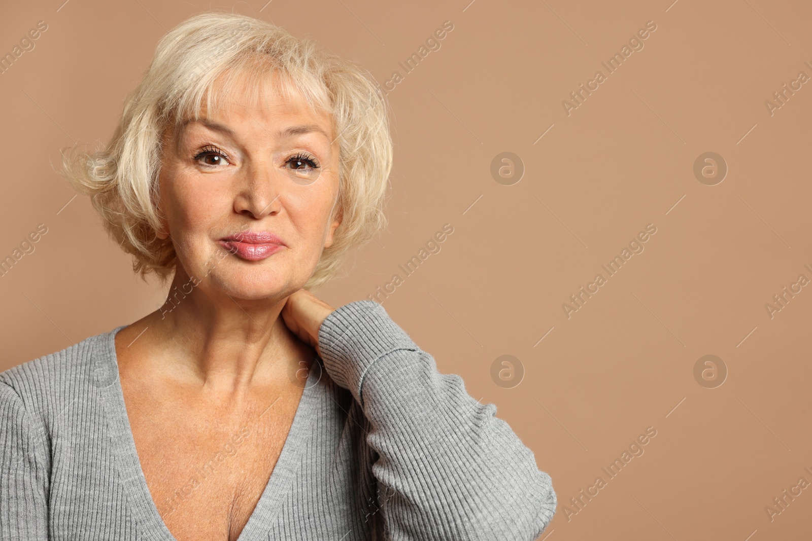 Photo of Portrait of beautiful senior woman on light brown background, space for text