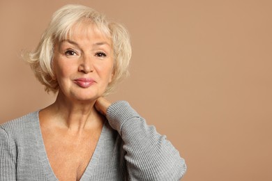 Portrait of beautiful senior woman on light brown background, space for text