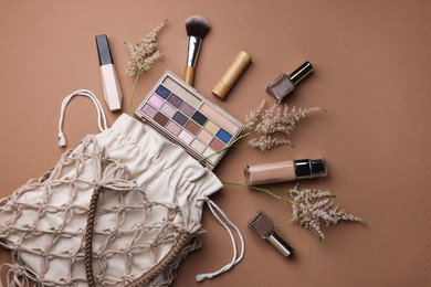 Photo of Handmade macrame shopping bag with makeup products and spikes on brown background, flat lay