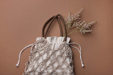 Photo of Handmade macrame shopping bag with spikes on brown background, top view