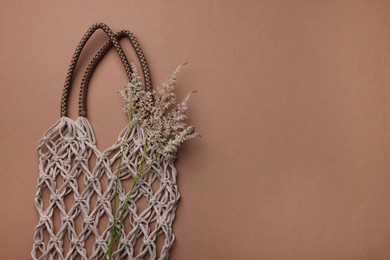 Photo of Handmade macrame shopping bag with spikes on brown background, top view. Space for text