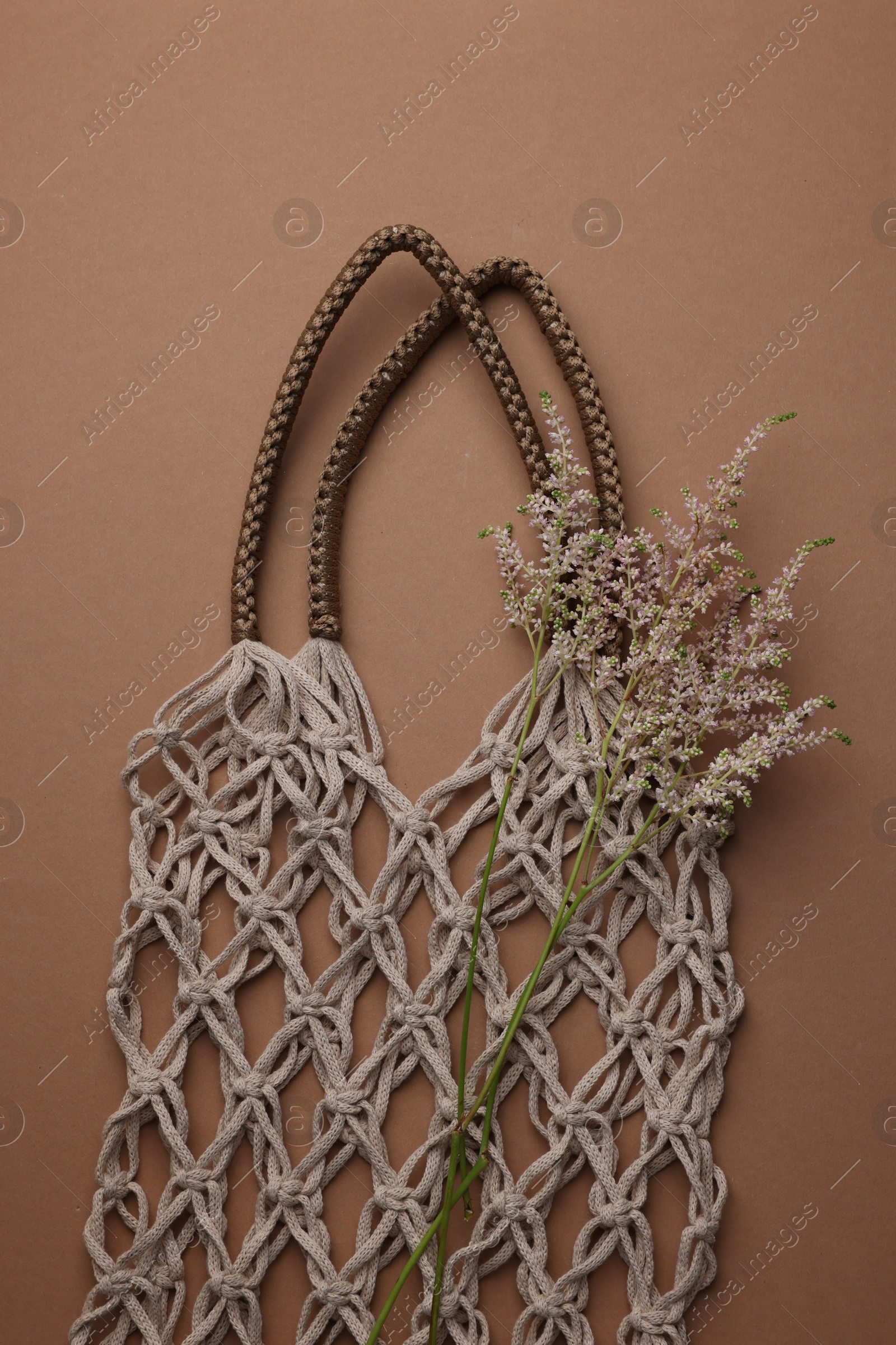 Photo of Handmade macrame shopping bag with spikes on brown background, top view