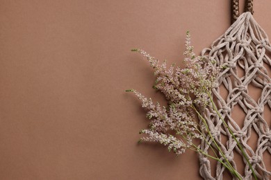 Handmade macrame shopping bag with spikes on brown background, top view. Space for text