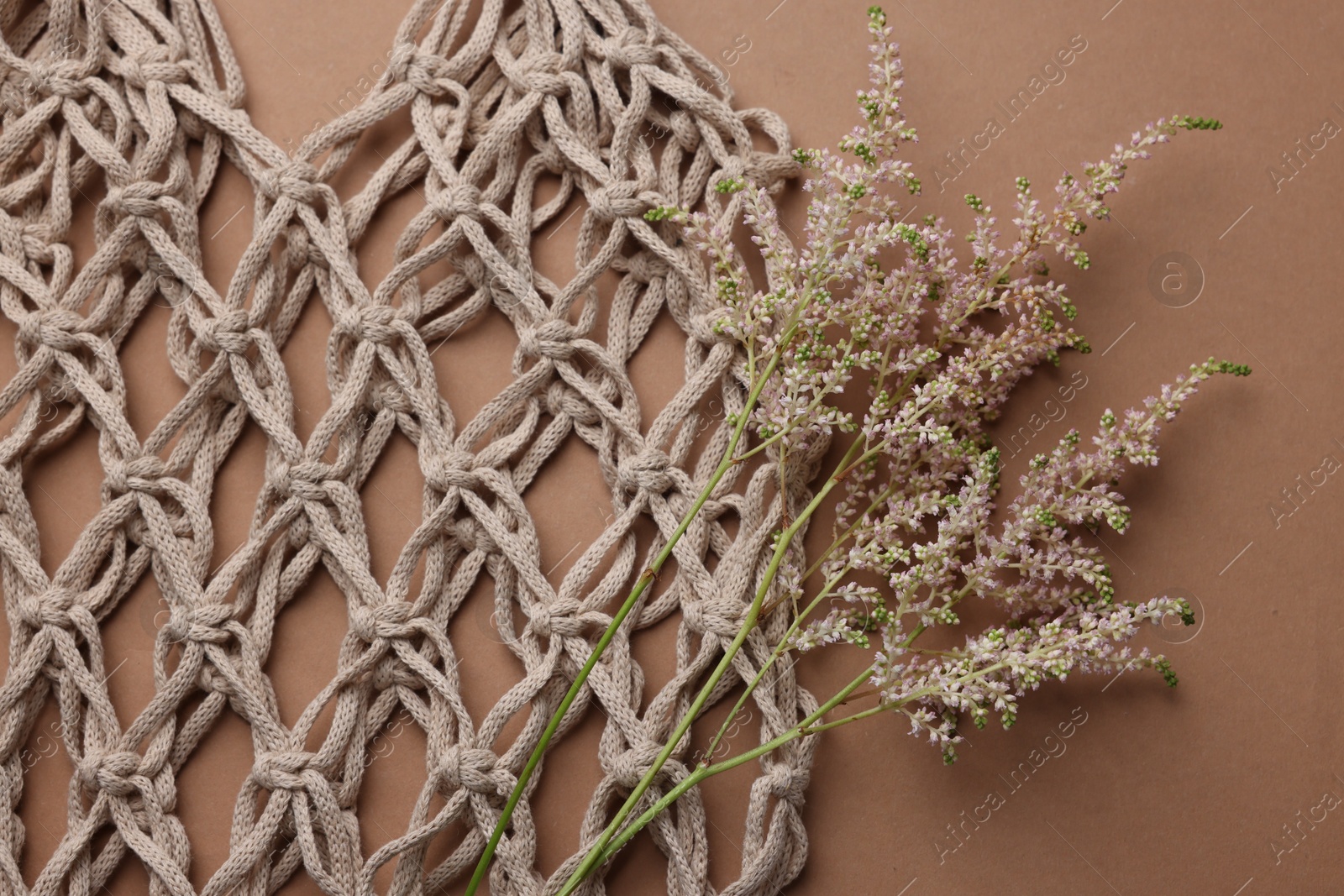 Photo of Handmade macrame shopping bag with spikes on brown background, top view